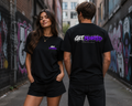 Two people wearing black t-shirts with a brand logo in an urban setting with graffiti.